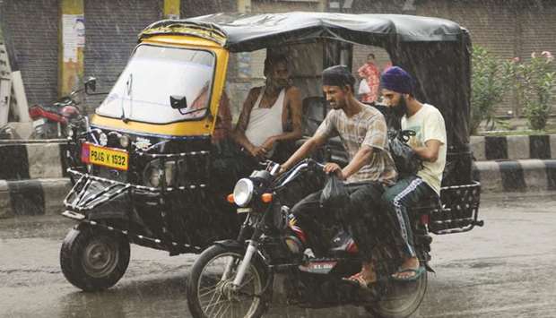 Commuters make their way along a road as rain falls in Amritsar in Punjab yesterday.