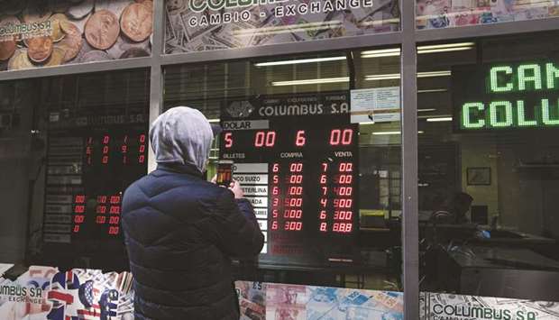 A pedestrian takes a photograph of an electronic monitor displaying the currency exchange rate in Buenos Aires on August 13. The International  Monetary Fundu2019s record loan to Argentina last year was supposed to turn the page on a troubled history. Itu2019s looking more like a case of deja vu.
