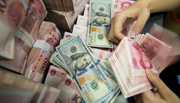A Chinese bank employee counts 100-yuan notes and US dollar bills at a bank counter in Nantong, Jiangsu province. Onshore spot yuan finished the domestic session at 7.1514 per dollar.