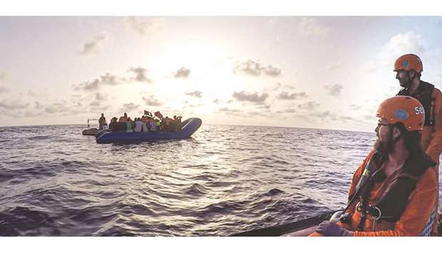 This handout picture taken on July 31 by German migrant rescue NGO Sea-Eye, shows members of the German migrant rescue charity helping people to get off from an overloaded rubber boat spotted in international waters off the Libyan coast.