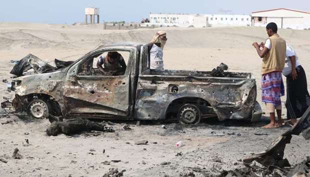 Yemeni fighters inspect burnt out armoured vehicles reportedly belonging to pro-government troops following yesterday's air strikes on Yemen's interim capital Aden.