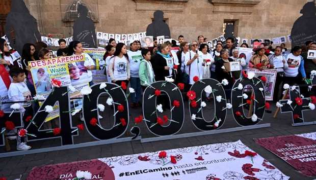 People hold pictures of missing persons in front of the National Palace during the commemoration of the International Day of the Disappeared in Mexico City
