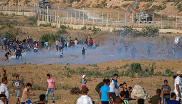 Palestinian protesters flee from tear gas fired by Israeli forces across the fence during clashes along the border with Israel near Bureij in the central Gaza Strip Friday
