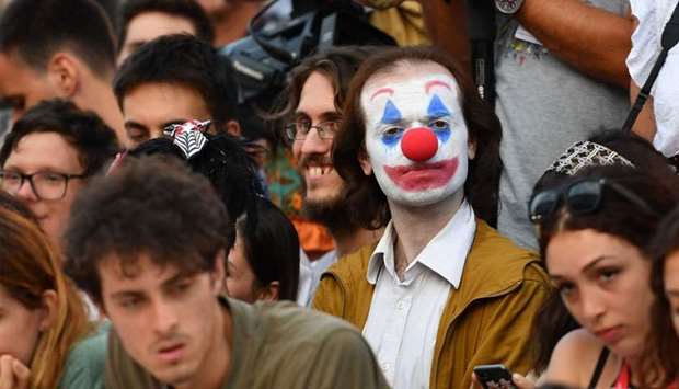 A festival goer wearing a clown make up waits in the public for guest's arrivals, prior to the screening of the film ,Joker,