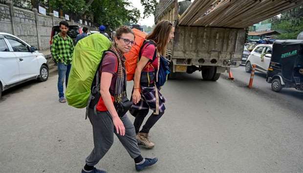 Tourists from Belgium walk on a road as they are going to leave Kashmir in Srinagar