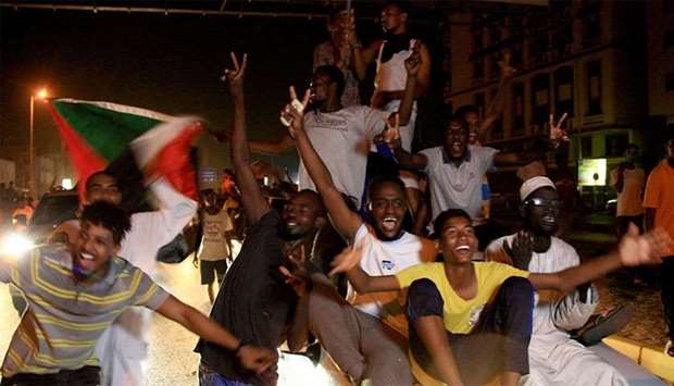 Sudanese demonstraters wave their national flag as they celebrate in Khartoum early on Thursday, after Sudan's ruling generals and protest leaders reached a ,full agreement, on the constitutional declaration.
