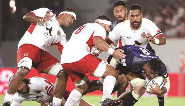 Ananaki Lelei Mafi of Japan (right) attempts to run past Tongau2019s players during the Pacific Nations Cup match in Higashiosaka, Osaka, yesterday. (AFP)