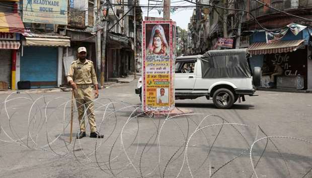 An Indian security personnel stands guard along a deserted street during restrictions in Jammu