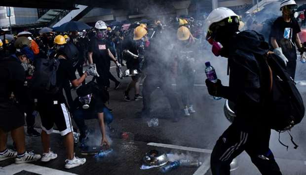 Protesters attempt to contain tear gas fired by the police in the Admiralty area during a general strike in Hong Kong
