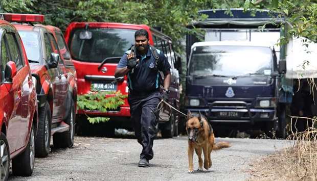 A police officer uses a sniffer dog as police search for 15-year-old Irish girl Nora Anne Quoirin who went missing from a resort in Seremban, Malaysia