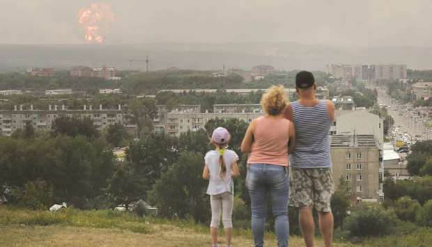 People watch flame and smoke rising from the site of blasts at an ammunition depot near the town of Achinsk, in the Krasnoyarsk region.
