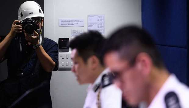 A photographer, wearing a protective helmet during a police press conference in protest of what journalists claim was excessive force used against them in recent street demonstrations, takes pictures at the police headquarters in Hong Kong