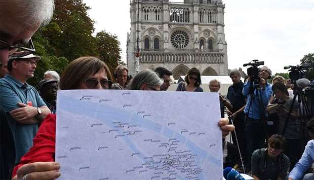 A woman shows a lead pollution levels map during a press point, on July 5, 2019 organised by the labour Union's General Confederation of Labour (CGT) and associations, in front of the Cathedral of Notre-Dame de Paris