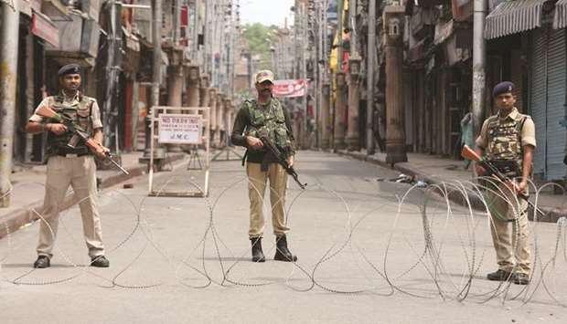 Security personnel stand guard along a deserted street during restrictions in Jammu yesterday.