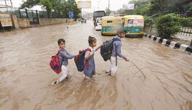 Schoolchildren wade through a flooded street after heavy rains in New Delhi yesterday.