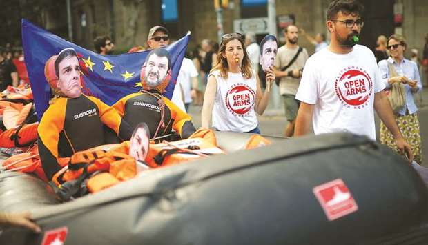 In this photo taken on July 13, protesters hold an inflatable boat bearing masks of Spanish Prime Minister Pedro Sanchez and Italian Deputy Prime Minister Matteo Salvini, during a demonstration in Barcelona called by Spanish non-governmental organisation Proactiva Open Arms against the criminalisation of migrant rescue missions.