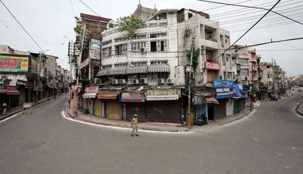 Indian policemen stand guard in a deserted street during restrictions in Jammu