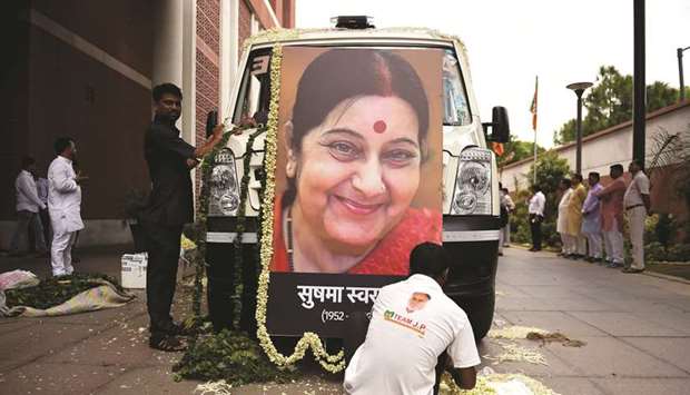 A worker decorates an ambulance with flowers and a picture of former foreign minister Sushma Swaraj at the Bharatiya Janata Party headquarters in New Delhi yesterday.