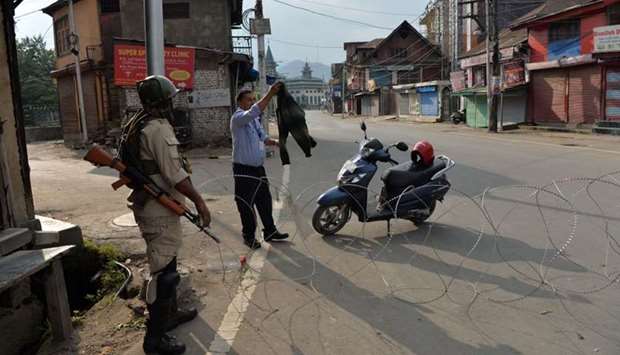 A security guard of a bank shows his sweater to a solider at a roadblock in Srinagar