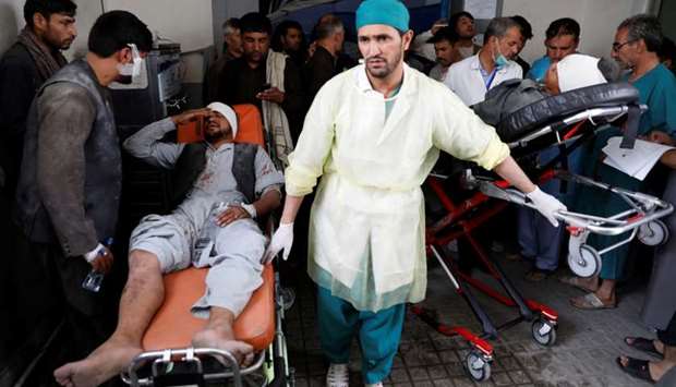 Men carry injured men to a hospital after a blast in Kabul