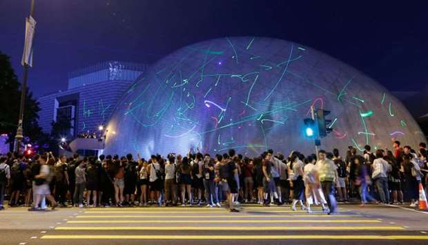 People watch the dots of laser pointers move across the facade of the Hong Kong Space Museum during a flashmob in Hong Kong