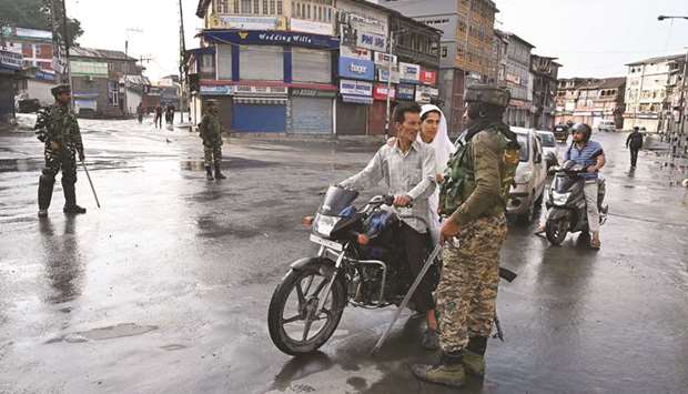A security personnel questions motorists on a street during a curfew in Srinagar yesterday.