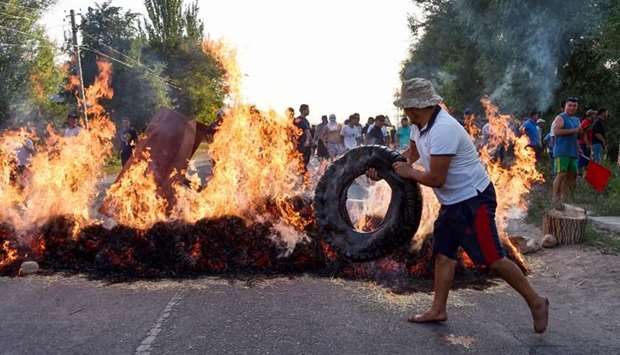 A protester puts a tyre on a burning barricade during clashes between supporters of Kyrgyzstan's former president and law enforcement, in the village of Koy-Tash, some 20 kilometres from Bishkek