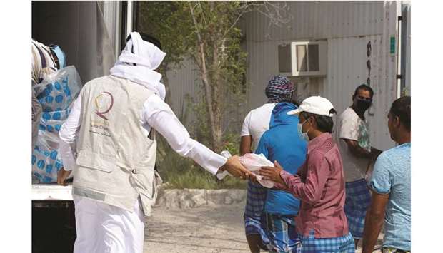 A QC volunteer distributing Udhiyah to workers.