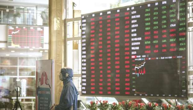 A worker wearing a protective suit stands at a temperature screening point in front of an electronic stock board at the Shanghai Stock Exchange. The Composite closed up 0.8% to 3,379.25 points yesterday.