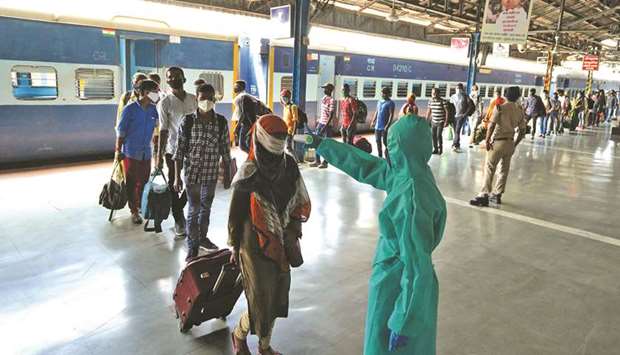 A worker wearing protective gear checks the temperature of a traveller at Dadar railway station, amidst the spread of the coronavirus disease in Mumbai, yesterday.