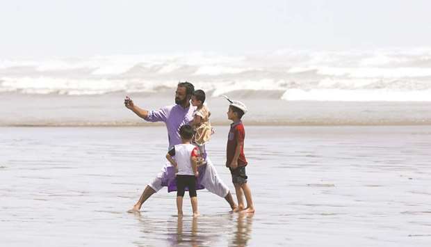 A man takes a u2018wefieu2019 with his children at Karachiu2019s Clifton beach.