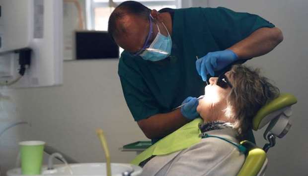 A dentist tends to a patient at Silveroaks Dental Surgery as it opens for non aerosol generating assessments in Milton Keynes, following the outbreak of the coronavirus disease, Milton Keynes, Britain