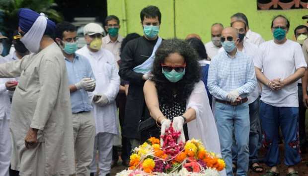 Wife of deceased Air India pilot Deepak Sathe places flowers on his coffin during his funeral in Mumbai, India