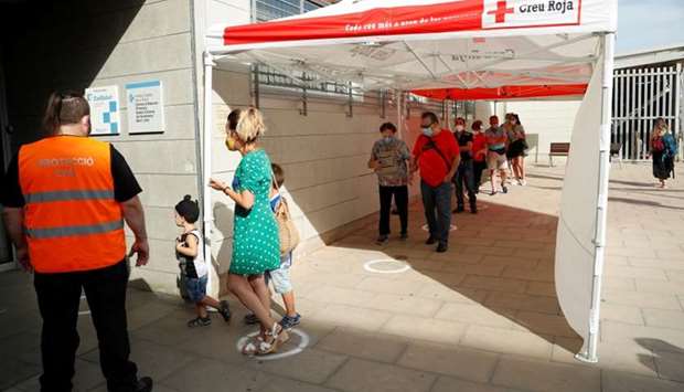 People queue outside a medical center to be tested for the coronavirus disease in Santa Coloma de Gramenet, north of Barcelona, Spain