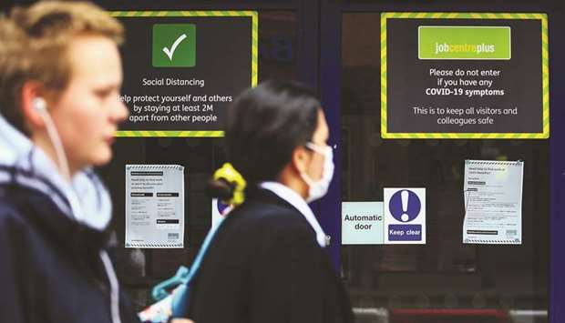 Pedestrians pass social distancing and coronavirus information signs on the entrance of a job centre plus employment office in London. Mounting job losses are expected as Britain winds down its job-retention scheme, which has covered around one in three private-sector jobs.