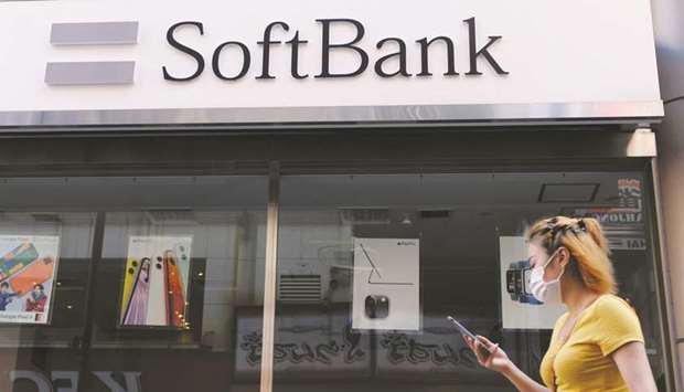 A woman walks past a SoftBank mobile store in Tokyo. SoftBank Group yesterday reported a $12bn quarterly net profit to June, recovering from eye-watering losses as tech stocks rally and the company sheds assets to shore up its finances.