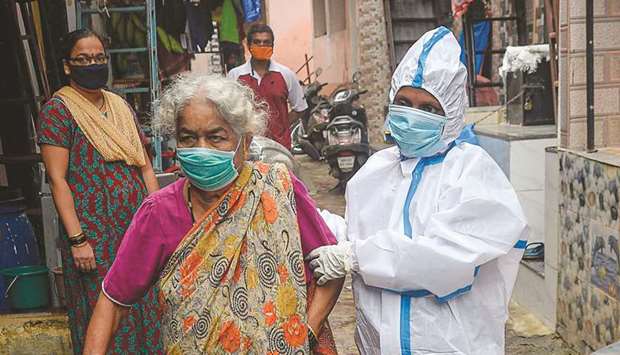 A health worker wearing Personal Protective Equipments (PPE) assists an elderly resident during a Covid-19 screening in the Dharavi slum in Mumbai yesterday.