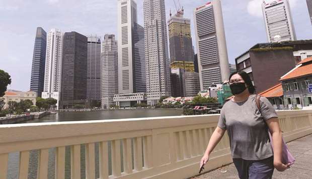 A woman walks across a bridge overlooking the financial business district in Singapore yesterday. Singaporeu2019s virus-hammered economy shrank almost 43% in the second quarter, in a sign that the countryu2019s first recession in more than a decade was deeper than initially estimated, official data showed yesterday.