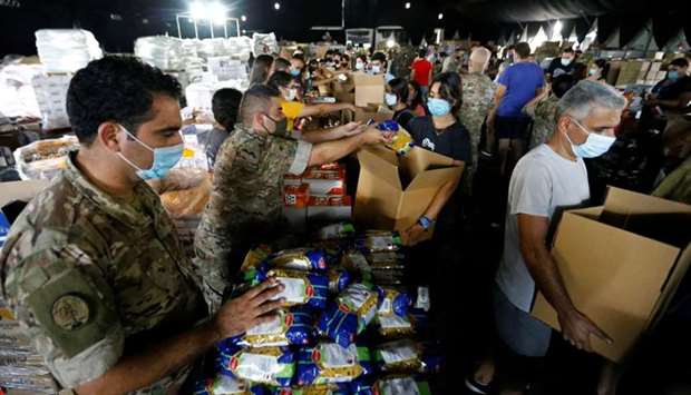 Lebanese army members and volunteers prepare aid to be distributed to people in the aftermath of a massive explosion in Beirut's port area, in Beirut, Lebanon