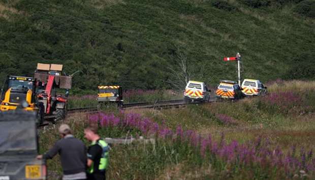 Emergency service vehicles ride along the tracks near the scene of a derailed passenger train, near Carmont, Stonehaven, Scotland