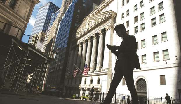 A pedestrian wearing a face mask looks at a smartphone while passing in front of the New York Stock Exchange. Bank traders who saved their firmsu2019 bottom lines in the first half of 2020 are facing a reality of the pandemic: Record revenue wonu2019t mean record bonuses, with most businesses facing declines of 10% or more.