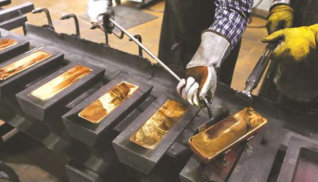 A worker uses a special tool to remove red hot gold ingots from their moulds in the foundry at the JSC Krastsvetmet non-ferrous metals plant in Krasnoyarsk, Russia. Gold rebounded yesterday, extending a series of wild swings that saw the metal hit a record on Friday before plunging to below $1,900 an ounce.