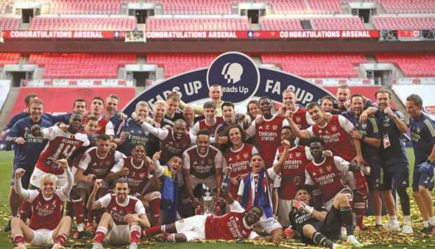 Arsenal players and staff celebrate winning the FA Cup after a 2-1 win over Chelsea in the final at the Wembley Stadium in London yesterday. (AFP)