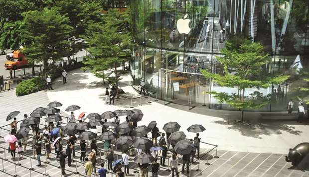 People holding umbrellas line up to enter the newly-opened Apple store in downtown Bangkok on Friday. Quarterly results from Apple, Amazon.com, Facebook and Alphabet on Thursday show the industry is capitalising on the crisis as  locked-down consumers use tech gadgets and the Internet for entertainment, social connection, shopping, learning and work.