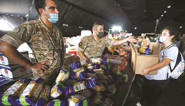 Lebanese army members and volunteers prepare aid to be distributed to people in the aftermath of a massive explosion in Beirutu2019s port area, yesterday.