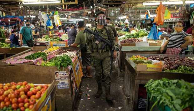 An armed police officer patrols at a public market where wearing face masks and face shields is mandatory, amid the coronavirus disease (Covid-19) outbreak in Taytay, Rizal province, Philippines