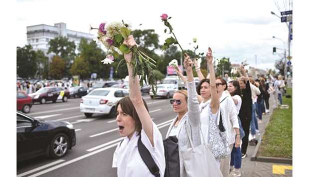 Women with flowers stand along a street in Minsk during their protest against police violence during recent rallies of opposition supporters.