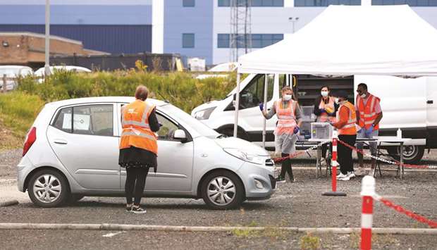 An NHS Covid-19 testing staff member collects a sample from a person in a car, across the road from the Greencore sandwich factory, amid the spread of the coronavirus disease, in Northampton, yesterday.