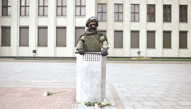 A Belarus law enforcement officer, with flowers left by protesters at his feet, stands guard in front of a government building during a rally in Minsk against police violence.