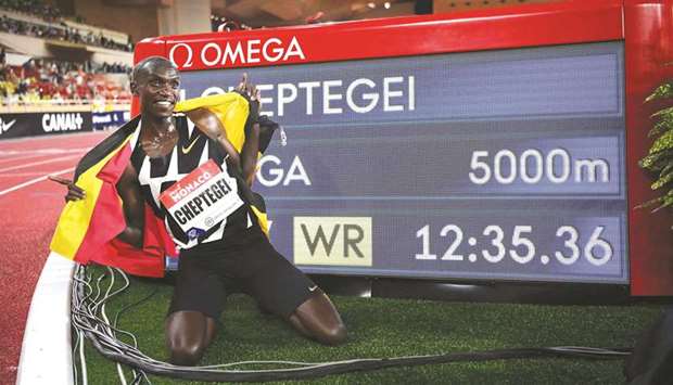 Ugandau2019s Joshua Cheptegei, wearing an Uganda  national flag on his shoulders, poses for pictures next to the timer screen after breaking the world record in the menu2019s 5000 metre event during the Diamond League Athletics Meeting at The Louis II Stadium in Monaco on Friday.